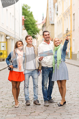 Image of group of smiling friends with map and photocamera