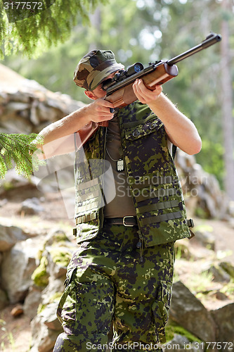 Image of soldier or hunter shooting with gun in forest