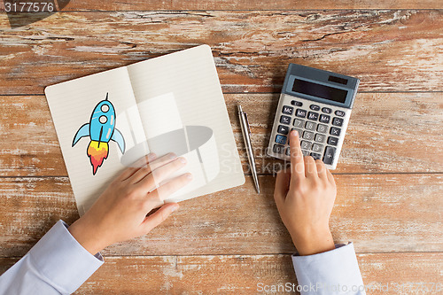 Image of close up of hands with calculator and notebook