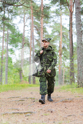 Image of young soldier or hunter with gun in forest