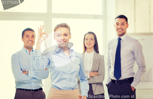 Image of smiling businesswoman showing ok-sign in office