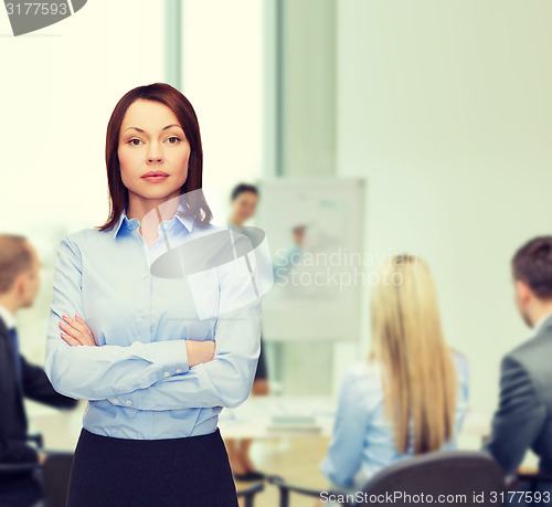 Image of smiling businesswoman with crossed arms at office