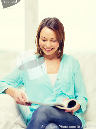 Image of smiling woman reading magazine at home