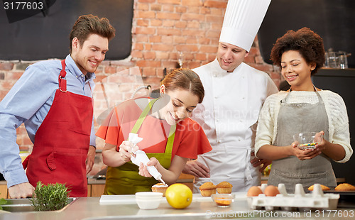 Image of happy friends and chef cook baking in kitchen