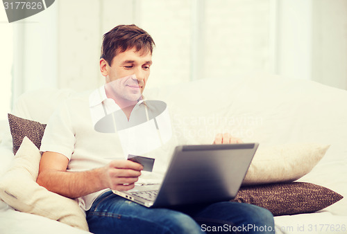 Image of man with laptop and credit card at home