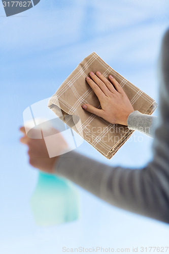 Image of close up of woman hands cleaning window with cloth