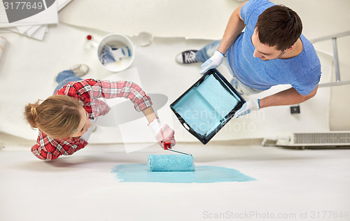 Image of couple with paint roller painting wall at home