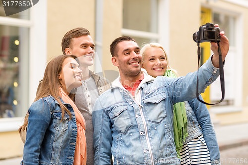 Image of group of smiling friends making selfie outdoors