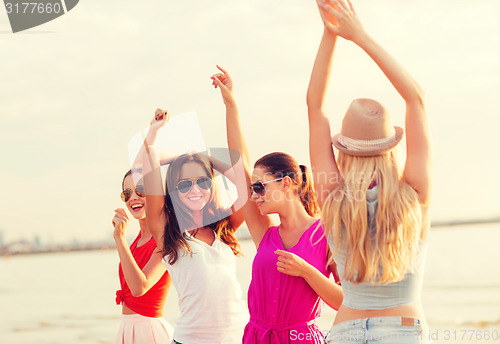 Image of group of smiling women dancing on beach