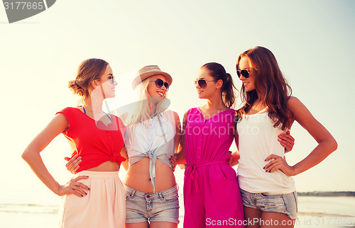 Image of group of smiling women in sunglasses on beach