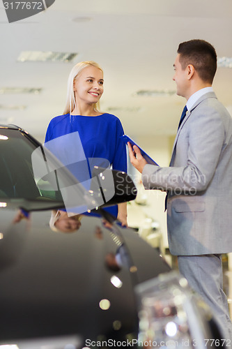 Image of happy woman with car dealer in auto show or salon