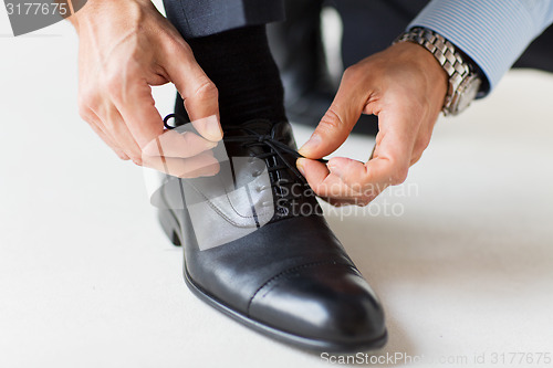 Image of close up of man leg and hands tying shoe laces