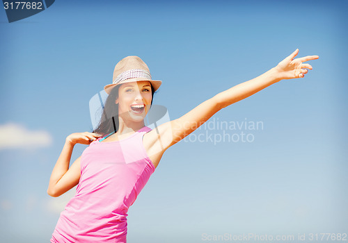 Image of girl in hat showing direction on the beach