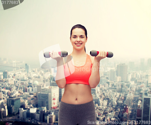 Image of young sporty woman with light dumbbells