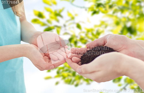 Image of close up of father and girl hands holding sprout