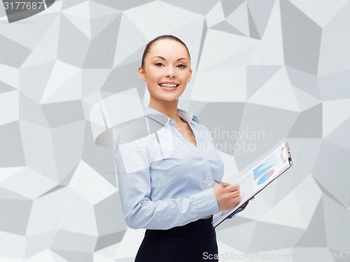 Image of young smiling businesswoman with clipboard and pen