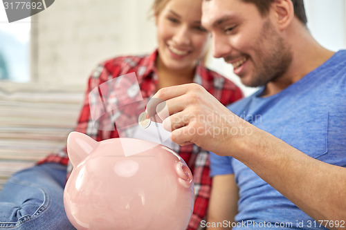 Image of close up of couple with piggy bank sitting on sofa