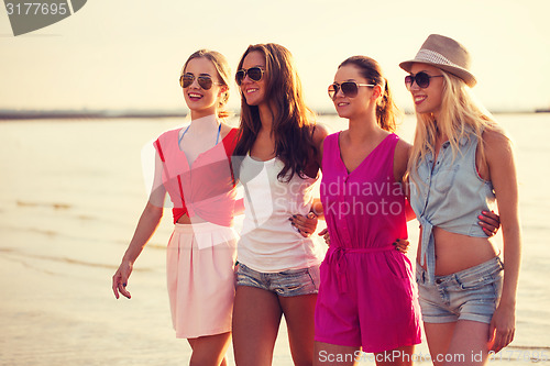 Image of group of smiling women in sunglasses on beach