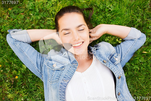 Image of smiling young girl with closed eyes lying on grass