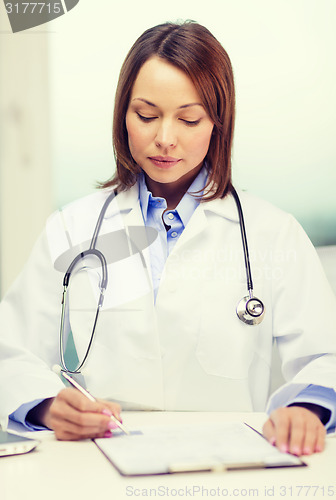 Image of busy doctor with laptop computer and clipboard