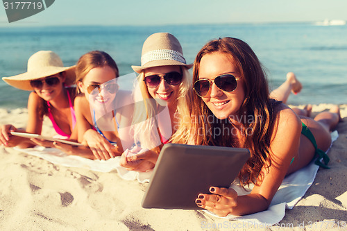 Image of group of smiling young women with tablets on beach