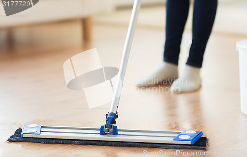 Image of close up of woman with mop cleaning floor at home