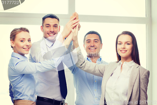 Image of happy business team giving high five in office