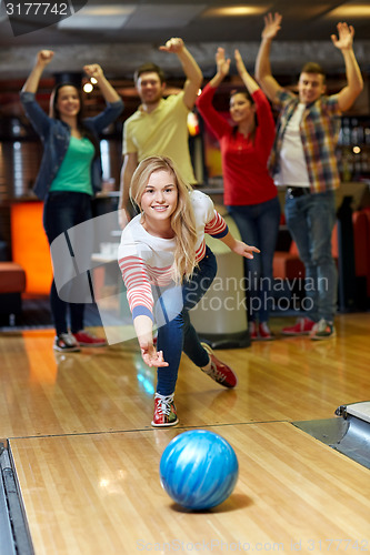 Image of happy young woman throwing ball in bowling club