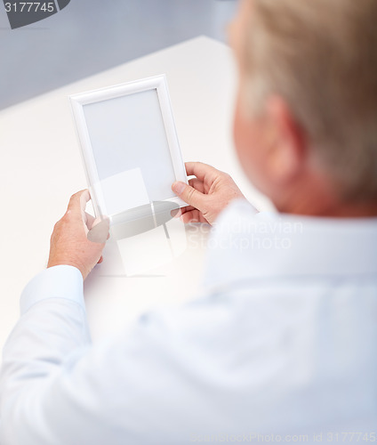 Image of close up of old man holding blank photo frame