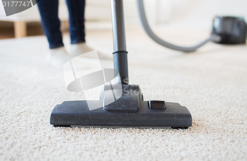 Image of close up of woman legs with vacuum cleaner at home