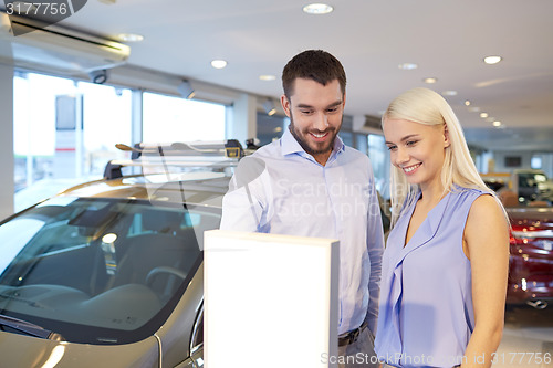 Image of happy couple buying car in auto show or salon