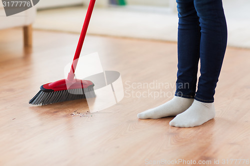 Image of close up of woman legs with broom sweeping floor