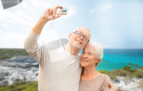 Image of senior tourists couple with camera photographing