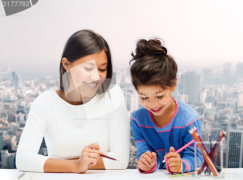 Image of happy mother and daughter drawing with pencils