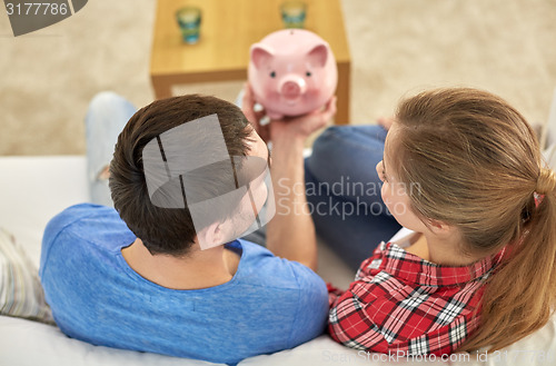 Image of close up of couple with piggy bank sitting on sofa