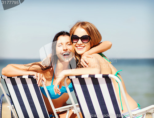 Image of girls sunbathing on the beach chairs