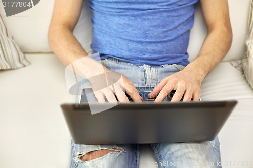 Image of close up of man typing with laptop at home