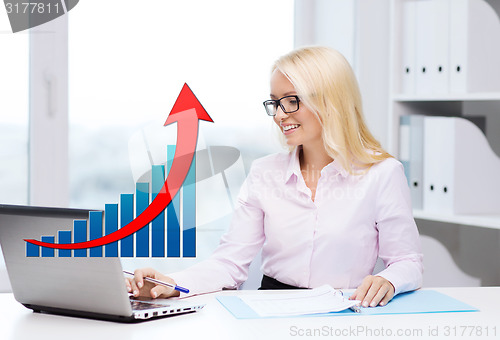 Image of smiling businesswoman with laptop and papers