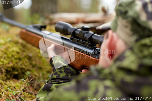 Image of soldier or hunter shooting with gun in forest