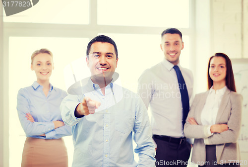 Image of businessman in office pointing finger at you