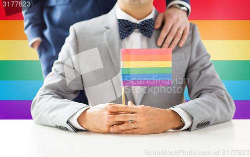 Image of close up of male gay couple holding rainbow flag