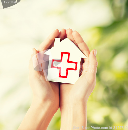 Image of hands holding paper house with red cross