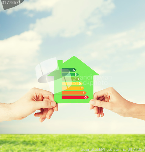 Image of hands holding green paper house