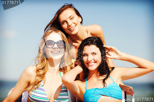 Image of girls sunbathing on the beach chairs