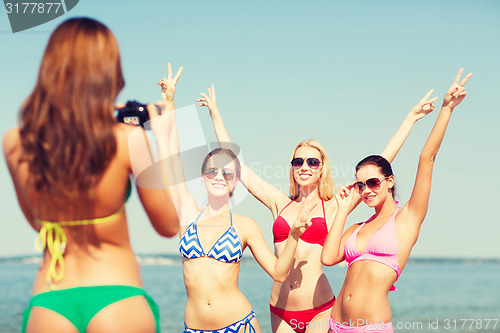 Image of group of smiling women photographing on beach