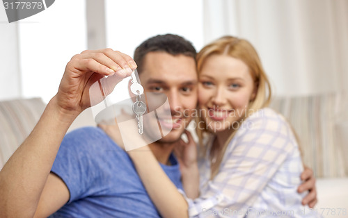 Image of smiling couple showing keys over room background