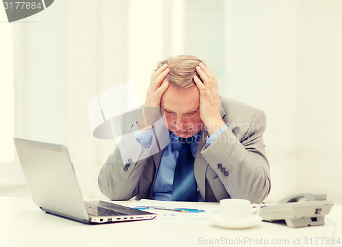 Image of upset older businessman with laptop and telephone