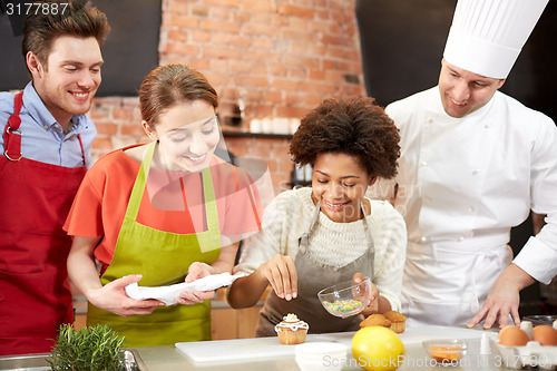 Image of happy friends and chef cook baking in kitchen