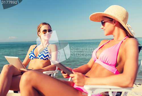 Image of smiling women with tablets pc computers on beach