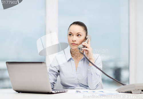 Image of businesswoman with phone, laptop and files